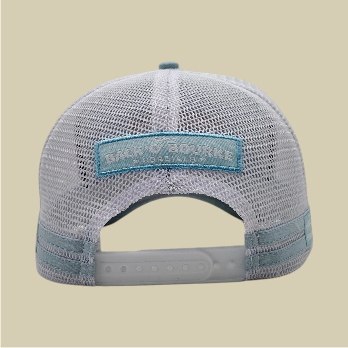 Back view of a white mesh trucker hat with a light blue patch reading 'BACK O' BOURKE CORDIALS' on a light beige background.