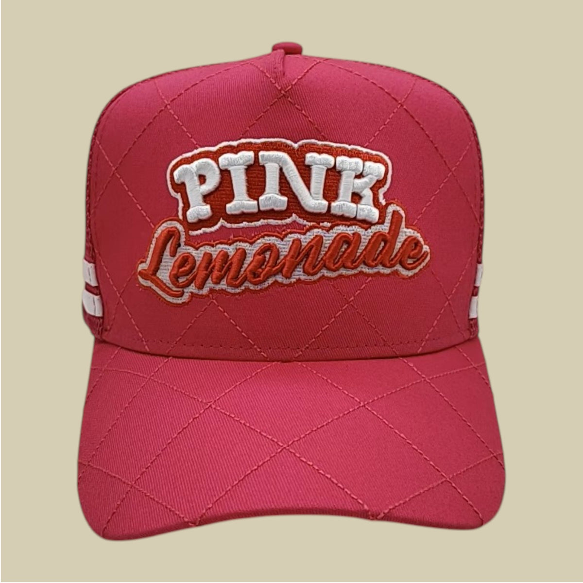 A pink quilted baseball cap with 'PINK Lemonade' embroidered on the front, set against a solid beige background.