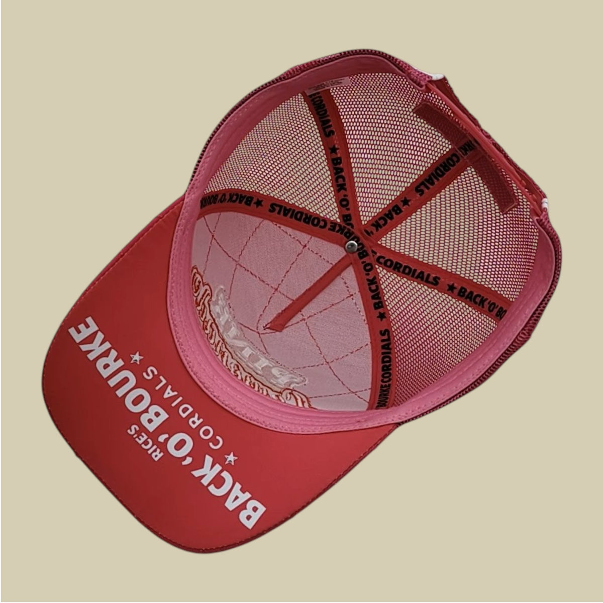 A hot pink trucker-style cap with a pink mesh back, featuring 'BACK O' BOURKE' and 'RICKS CORDIALS' printed in white on the front panel, and 'BACK O' BOURKE' printed in black on the suspension straps.
