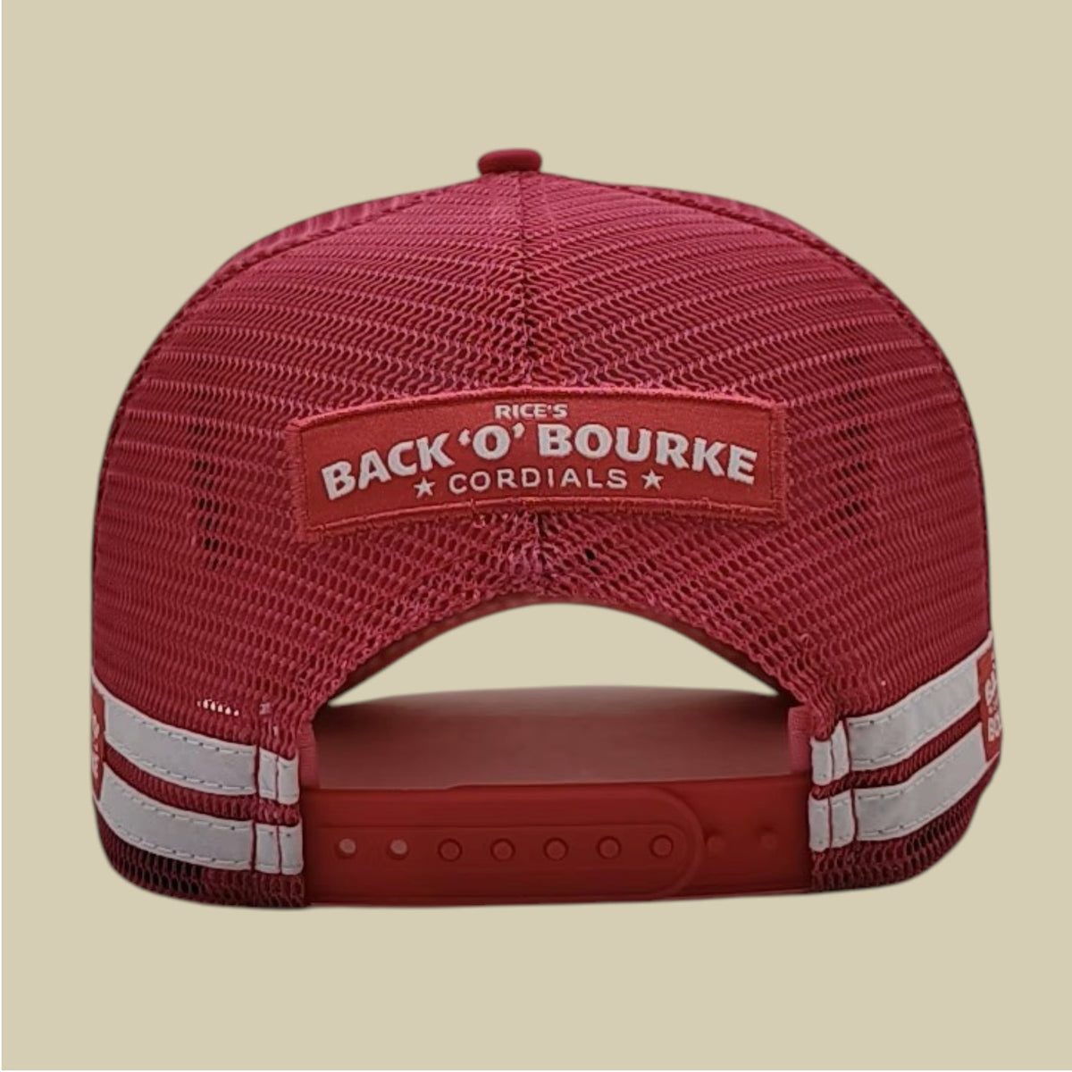 A hot pink trucker-style cap shown from the back, featuring a red mesh back, a pink patch with white text reading 'Rice's Back 'O' Bourke Cordials,' and white reflective stripes on the side straps, set against a solid beige background.